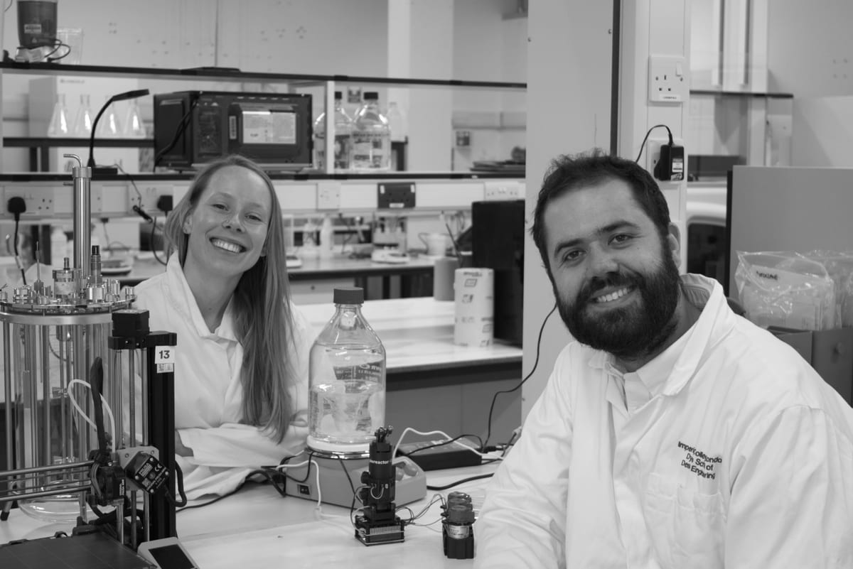 Zoe Woods and Noah Sprent in the lab beside a bioreactor